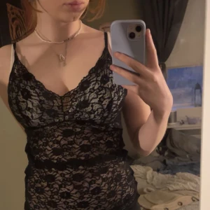 Svart spets topp - Snygg spets topp med smala axelband och ett vackert spetsmönster. Den har en figurnära passform. Spets framsida och svart baksida. Storlek S/M (stretch).