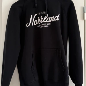 Svart hoodie från SQRTN - Säljer en svart hoodie från SQRTN med texten 'Norrland' i vitt på bröstet i bra skick. Tröjan har en justerbar huva med dragsko. 