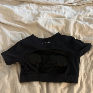 Svart  topp från Nvgtn med öppen rygg - Säljer en svart kortärmad topp från Nvgtn. Toppen har en öppen rygg och är croppad. Toppen har inbyggda pads. Storlek S