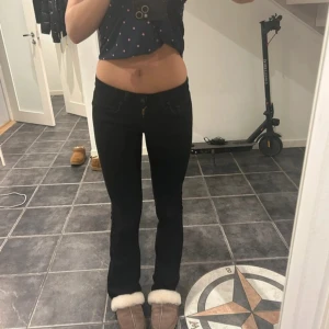 Svarta bootcut jeans från Levi's - Säljer ett par svarta Levi's low bootcut jeans. De har en klassisk femficksdesign och är perfekta för en avslappnad stil. Jeansen har en knappgylf och är tillverkade i ett slitstarkt material.