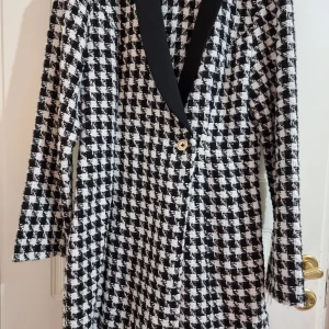 Svartvit rutig kappa från Shein - Snygg svartvit rutig kappa från Shein med en elegant svart krage och en dekorativ guldknapp. Perfekt för att ge din outfit en stilfull touch.