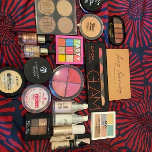 Blandat sminkset med paletter och foundations - Ett varierat sminkset med flera paletter och produkter från märken som NYX, e.l.f., och W7. Innehåller ögonskuggspaletter i olika färger, foundations, highlighter, och puder. Perfekt för att skapa olika sminklooker.