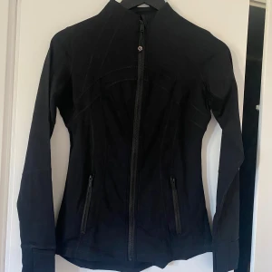 Svart träningsjacka  - Snygg svart träningsjacka med figurnära passform. Jackan har dragkedja framtill, hög krage och två fickor med dragkedja. Perfekt för träning eller som ett extra lager. Jackan är XS men passar S. Jackan är köpt på Tradera men säljer pga av att den var för liten. Skriv vid frågor (saknar kvitto där av priset). Har möjlighet att mötas upp i centrala Stockholm.