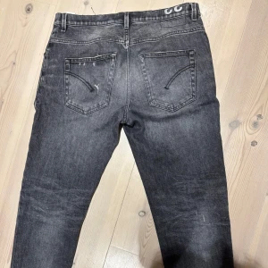Dondup Jeans - Säljer ett par mörkgråa dondupjeans med snygga slitningar på båda benen. Jeansen är i bra skick,hör av er för frågor eller bilder, storlek 33, personen på bilden är 187