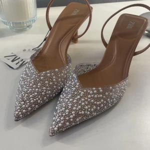 Glittriga klackskor med pärlor från Zara - Säljer ett par eleganta pumps från Zara med spetsig tå och klack. Skorna är täckta av pärlor och glittrande stenar för en riktigt lyxig känsla. Perfekta till bal eller nyår❤️ Nypris 650kr, säljer för 500