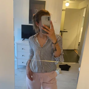 Randig skjorta med krage - Snygg skjorta med svartvita ränder och klassisk krage. Skjortan har långa ärmar och knappar framtill. Perfekt för en stilren och avslappnad look.