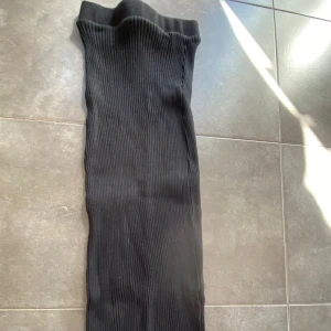 Svart ribbad tajt kjol från Zara, stl S - Svart ribbad tajt kjol från Zara. Kjolen är stretchig och har en bekväm passform, perfekt för en avslappnad stil. Tillverkade i mjukt bomullsmaterial som känns skönt mot huden.