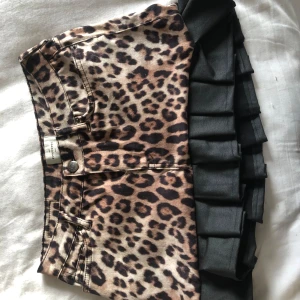 Leopardmönstrad kjol med volangkant - Säljer en kort leopardmönstrad kjol från H&M med svart volangkant nedtill. Kjolen har klassisk jeansmodell med fickor bak och fram samt knapp och dragkedja. Perfekt statement-plagg för dig som gillar djurmönster!