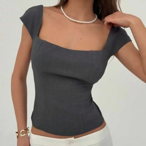 Mörkgrå figursydd topp med fyrkantig ringning - Snygg mörkgrå topp med figurnära passform och fyrkantig ringning. .