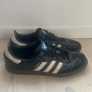 Adidas Samba skor - Klassiska Adidas Samba sneakers i svart skinn och de ikoniska tre ränderna på sidorna. Använda men har tagits hand om väl. Storlek 44 2/3 så passar både för 44 och 45. Kontakta gärna om frågor. Pris kan diskuteras. 