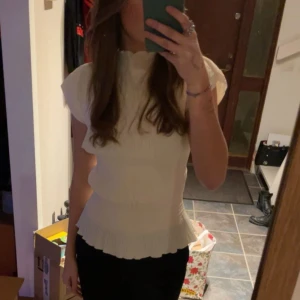 Vit blus med volang - Säljer en söt vit blus med ribbad struktur och volangkant nertill. Passar perfekt till alla tillfällen. Använd fåtal gånger så varan är i bra skick, pris kan diskuteras! Färgen är mer naturvit