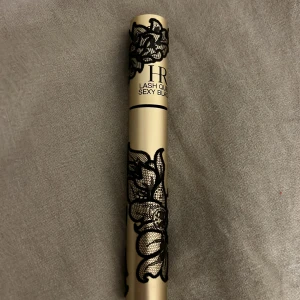 Lash Queen Sexy Black Mascara - Snygg mascara i guldig tub med svart spetsmönster från Helena Rubinstein. Borsten är böjd och tät för att ge volym och separera fransarna. Perfekt för att framhäva ögonfransarna med en intensiv svart färg.