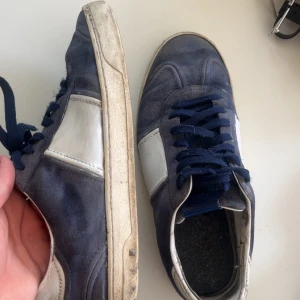 Valentino flycrews  - Säljer ett par blåa Valentino flycrews sneakers med vita detaljer och mörkblå snörning. Skorna har en unik kamouflagemönstrad sula och är tillverkade i mocka och skinn. Perfekta för dig som vill ha något extra till våren.