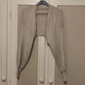 Beige bolerotopp - Säljer denna jättegulliga beiga stickade bolerotoppen. Använd fåtal gånger så i nyskick, med en ribbad struktur! Nypris: ≈499kr