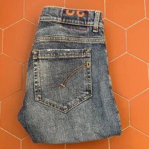 Blå Dondup jeans - Klassiska blå jeans med raka ben och snygga orangea sömmar på bakfickorna. Jeansen har fem fickor, normal passform och en diskret tvättad look. Perfekta för en avslappnad stil och passar till det mesta i garderoben. Priset kan diskuteras! 😎