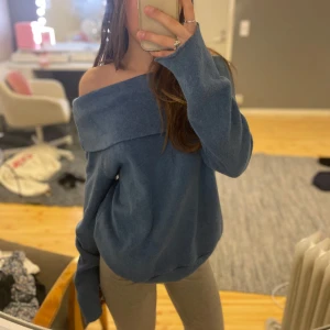 Blå offshoulder stickad tröja - Säljer en blå stickad tröja med offshoulder-design. Tröjan har en bred krage som går över axlarna och är långärmad. Köpt på second hand och den har inga lappar så jag vet inte vad det är för märke. Väldigt mysigt och luftigt material som inte sticks eller kliar 💗