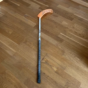 Innebandyklubba från Oxdog med orange blad - Säljer en innebandyklubba från Oxdog med ett orange plastblad och vitt skaft med svarta och guldiga detaljer. Greppet är lindat med grå tejp. Perfekt för dig som gillar innebandy och vill ha en lätt och smidig klubba.