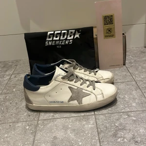  Golden Goose - Säljer ett par vita sneakers från Golden Goose.Skorna har grå snörning och platt sula. Klassisk och stilren modell med GGDB/SSTAR-tryck på sidan.