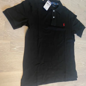 Svart pikétröja från Ralph Lauren - •Säljer en jätte stilig Svart Ralph Lauren Piké.  •Den är inte använd bara testad, jätte bra skick och inga fläckar eller hål.  •Och det är storlek M och måtten finns på dem sista bilderna •Priset kan diskuteras och skickar inom 24 Tim 💨😊