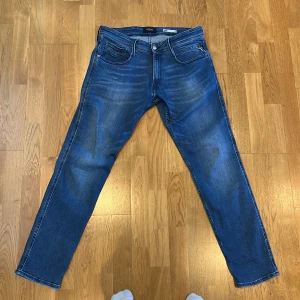 Blå Replay Anbass jeans straight fit - Säljer ett par blå Replay Anbass slim jeans med klassisk femficksdesign och tillverkade i mjukt denimtyg. Perfekta för dig som gillar en tidlös och clean look. Använda bara typ 4-5 gånger så helt nya egentligen Bara att skriva om du har eventuella frågor. Storlek: W34 L32.