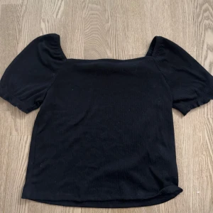 Svart topp med puffärm från H&M - En svart topp från H&M med korta puffärmar och fyrkantig halsringning. Enkel att matcha med både jeans och kjol! Endast använd ett fåtal gånger
