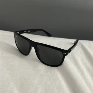 Svarta Ray-Ban boyfriend solglasögon - Snygga svarta Ray-Ban boyfriend solglasögon med klassisk rektangulär form och mörka linser. Kommer med original Ray-Ban fodral, putsduk och rengöringsduk. Perfekt accessoar för att höja din stil och skydda ögonen mot solen. Mycket bra skick, knappt använda. 