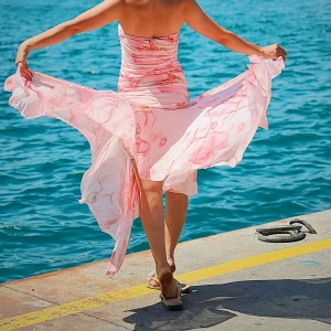 Lång rosa axelbandslös klänning - Säljer en romantisk långklänning i ljusrosa med blommigt mönster. Klänningen är axelbandslös och har en flowy, luftig passform som ger en riktigt somrig vibe. Perfekt för varma dagar vid havet eller när du vill känna dig extra fin.