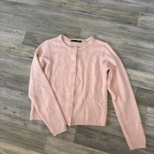 Ljusrosa kofta från 157, storlek S - Säljer en söt ljusrosa kofta från 157 i storlek S. Koftan har rund hals, långa ärmar och knäpps med matchande rosa knappar framtill. Mjuk stickad känsla som är perfekt för lager-på-lager och chill dagar. Passar dig som gillar enkel och clean stil.