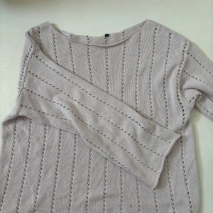 Ljusbeige stickad tröja med hålmönster - Superfin ljusbeige stickad tröja med lång ärm och snyggt hålmönster i ränder. Tröjan har en relaxed fit och är perfekt att slänga på sig när det är lite kyligt. Passar till jeans eller kjol för en chill look.Den är ganska tunn och perfekt till hösten! Halsen är avklippt så det är jättesnygg ringning