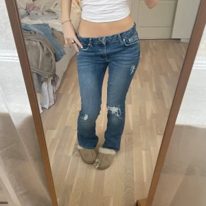 Blå jeans med slitningar - Säljer ett par jeans från Gina!! Hålen och slitningarna har jag gjort själv! Inga synliga defekter🥰 Passar mig som är 160cm. Storleken är 152 så typ xs/xxs 