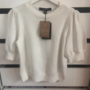 Vit stickad tröja från Vero Moda - Supersöt helt ny vit stickad tröja från Vero Moda med puffade ärmar och ribbade muddar. Rund halsringning och mjukt material som känns skönt mot huden. Perfekt för dig som gillar en clean och fräsch look med lite extra volym på axlarna.