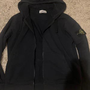 Stone Island zip  - Säljer nu min stone Island Hoodie i storlek M då jag knappt använder den längre. Tröjan är i väldigt bra skick finns inga trasiga hål eller något liknande med andra ord tröjan är helt hel. Tröjan är en lätt ganska mörk blå färg. Tröjan är äkta qr osv finns 