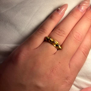 Guldfärgad ring med nitar - Cool guldfärgad ring med nitar runt om. Ringen har en blank finish och känns edgy och unik, perfekt för dig som vill sticka ut. Passar både som statement piece eller att kombinera med andra ringar.