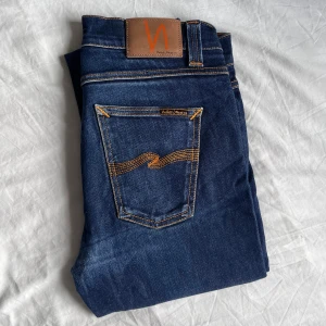 Mörkblå jeans från Nudie - Säljer ett par mörkblå jeans från Nudie Jeans. Modell: lean Dean. Storlek 32/30. Små i storleken.  Liten lagning i skrevet men annars helt fel fria.