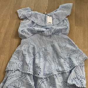 Ljusblått matchande set från RYVLS - Supersöt ljusblått set med tjol och kortare topp.  Det har broderade hålmönster och volanger. Toppen har korta ärmar och smock i midjan för en stretchig  passform. Lappen sitter fortfarande kvar på toppen och har aldig använts