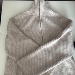 Beige ribbad half zip tröja H&M - Säljer en beige ribbstickad tröja från H&M med hög krage och half zip-dragkedja. Materialet är mjukt och stickat. Använd 1 gång! 