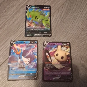 Pokémon V-kort: Tyranitar V, Empoleon V & Mimikyu V - Tre coola Pokémon V-kort: Tyranitar V, Empoleon V och Mimikyu V! Perfekt för dig som vill boosta din samling eller spela med kraftfulla och populära Pokémon. Korten har snygg design och är favoriter bland unga samlare och spelare.