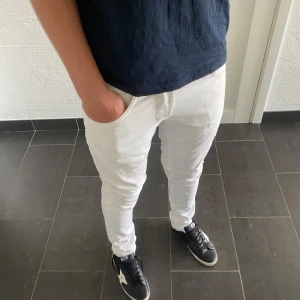 Dondup George  - Säljer ett par fräscha vita skinny fit jeans från Dondup i storlek 32. Jeansen har klassisk femficksdesign, diskreta slitningar och snygga detaljer. Perfekta för dig som gillar en tight passform och vill sticka ut med en ljus look.
