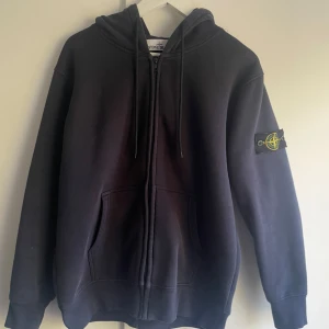 Mörkblå hoodie från Stone Island - Snygg mörkblå Stone island hoodie i skönt material och bra skick. Storleken är M.  Tveka inte på att höra av dig om du har frågor