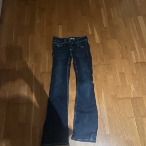 Mörkblå bootcut jeans Gina Tricot - Mörkblå jeans från Gina Tricot i bootcut-modell med kontrastsömmar och klassisk femficksdesign. Snygg passform med utsvängda ben och låg midja. Perfekta för dig som gillar en retroinspirerad look.