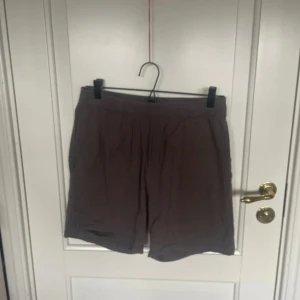 Grå loose shorts från 157 S - Snygga gråa shorts från 157 i storlek S. Modellen är loose fit med elastisk midja och tillverkad i ett lätt syntetmaterial som är perfekt för varma dagar. Enkla och stilrena utan mönster eller extra detaljer, passar dig som gillar chill och enkel stil.