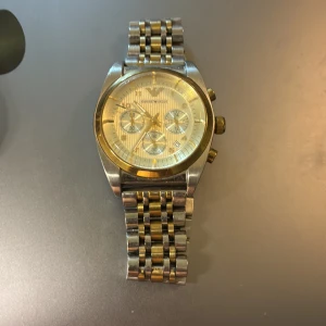 Emporio Armani klocka guld/silver - Stilren Emporio Armani AR-0396 klocka i rostfritt stål med tvåfärgad länk i guld och silver. Pris kan diskuteras