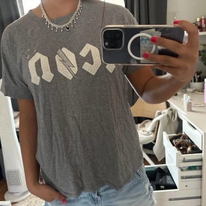 Grå t-shirt med tryck från Hunkydory - Grå t-shirt från Hunkydory med coolt vitt tryck framtill och avslappnad passform. T-shirten har rund hals och korta ärmar, perfekt till jeans eller shorts. Materialet är mjukt bomull som känns skönt mot huden. Snygg och enkel att styla för en chill look. Lappen håller på att åka av