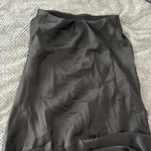 Svart långkjol från Lindex - Säljer en svart långkjol från Lindex i storlek 140. Kjolen har en slät och glansig yta som ger en snygg och stilren look. (Siden material)Perfekt för dig som gillar enkla och klassiska plagg. Materialet känns mjukt och följsamt mot huden.🖤