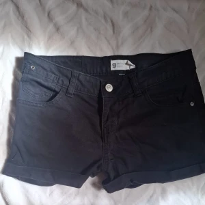 Svarta jeansshorts från Gina Tricot - Svarta jeansshorts från Gina Tricot med klassisk femficksdesign, uppvikta benslut och silverfärgade detaljer. Snygg passform och perfekt längd för sommaren. Köpta på vinted, Använda enstaka gånger! Skriv för mått! 💕
