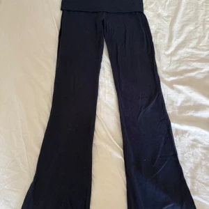 Mörkblå  butcut yoga från Gina Tricot - Säljer ett par mörkblå utsvängda byxor från Gina Tricot i mjukt bomullsmaterial. Byxorna har en hög midja och långa, vida ben som ger en chill och trendig look. Perfekta att matcha med en crop top eller hoodie för en avslappnad stil.