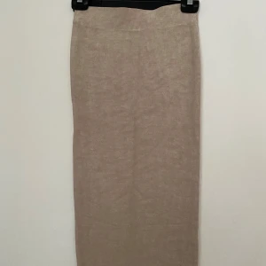 Beige ribbad långkjol Gina Tricot - Snygg beige långkjol från Gina Tricot i ribbad stickad kvalitet. Kjolen har en rak och slim passform med bred resår i midjan för extra komfort. Perfekt att matcha med en enkel topp eller hoodie för en chill look.