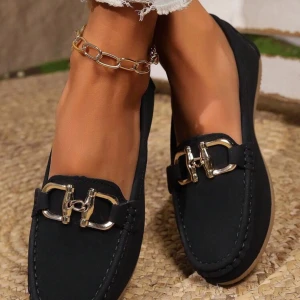 Svarta loafers med metallspänne - Snygga svarta loafers med dekorativt metallspänne i silver på ovansidan. Skorna har en rund tå och platt sula i beige, vilket ger en stilren kontrast. Tillverkade i mocka för en mjuk och lyxig känsla. Perfekta att matcha med jeans eller chinos för en cool look.