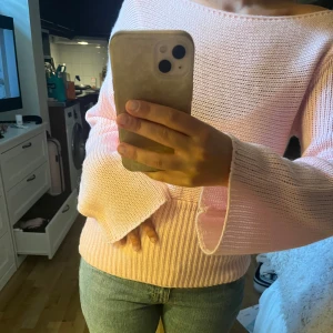 Ljusrosa stickad tröja med vida ärmar - Superfin ljusrosa stickad tröja med bred ribbad kant nedtill och riktigt sköna, vida ärmar. Tröjan har en snygg offshoulder-ringning som ger en chill vibe och är perfekt att matcha med jeans. Mjuk och bekväm, passar dig som gillar pastell och oversized känsla.