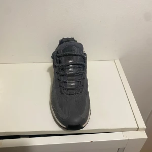 Nike Air Max 95 mörkgrå sneakers - Nike Air Max 95 sneakers i mörkgrått med vita detaljer på sulan. Skorna har en klassisk chunky siluett, mesh och syntetmaterial, samt snörning framtill. Ikonisk Air Max-dämpning i sulan för extra komfort. Perfekt för dig som gillar streetwear och sportig stil.